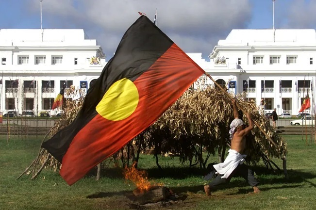 person holding australian aboriginal flag